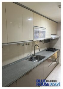 奶茶色一字型廚具，搭配灰色人造石檯面與隱藏式把手設計